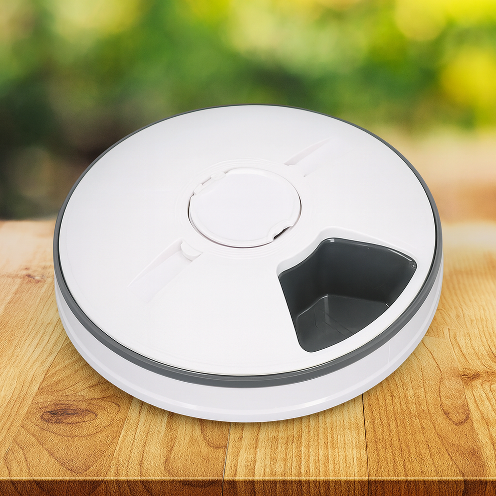 Round white and gray device on a wooden surface with a blurred green background