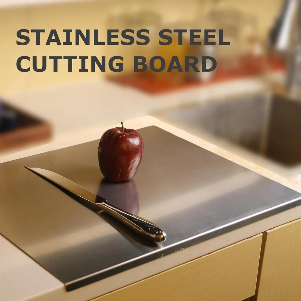 Stainless steel cutting board with an apple and knife on a kitchen counter.